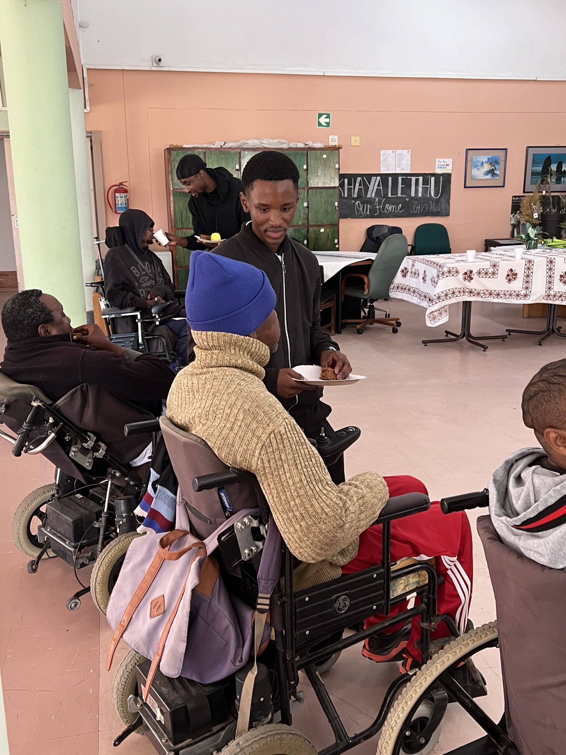 Residents and volunteers together in the hall at Langa Cheshire Home